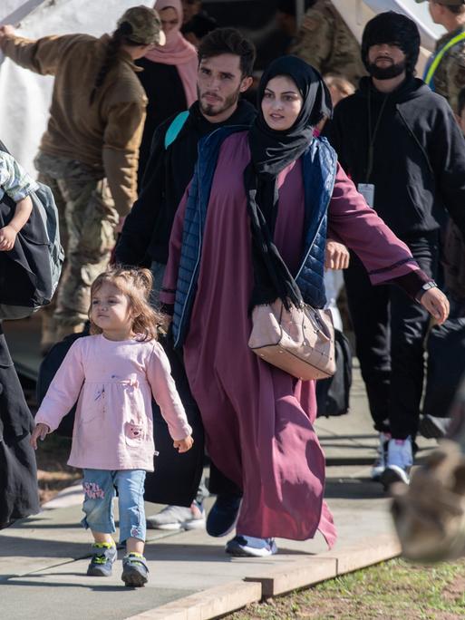 Kinder und Familien aus Afghanistan tragen vor ihrem Abflug in die USA ihr Gepäck zu einer Sammelstelle. 