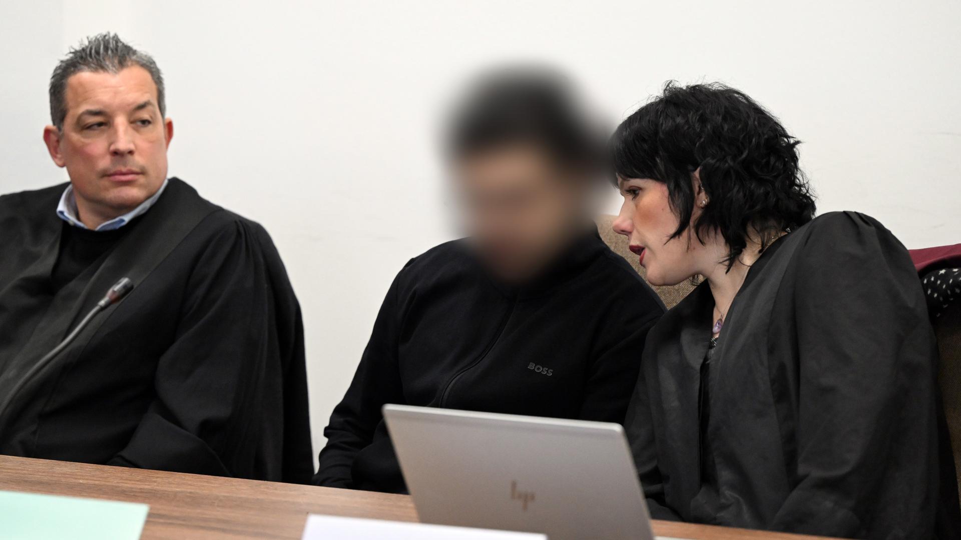 Der Angeklagte wartet mit seinen Verteidigern Wolf Bonn (l) und Franziska Ernst auf den Prozessbeginn. Sein Gesicht ist unkenntlich gemacht worden.