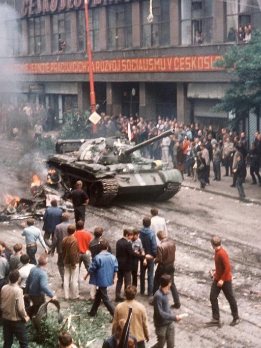 Eine Menschenmenge umringt am ersten Tag der Besetzung in der Prager Innenstadt einen russischen Panzer, der neben einem ausgebrannten Fahrzeug zum Stehen gekommen ist. 