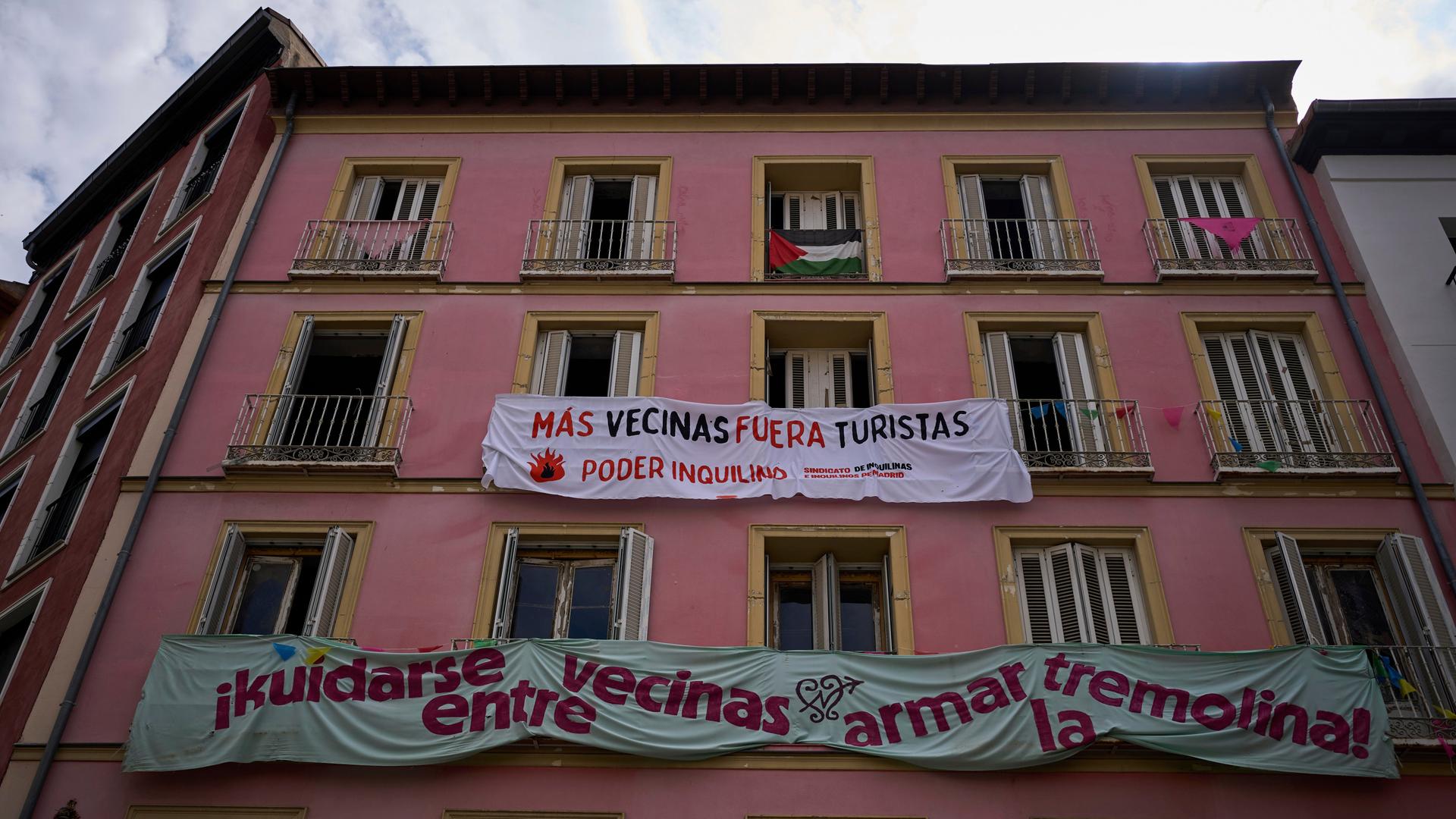 An der Fassade eines Gebäudes in der Innenstadt von Madrid hängen Transparente mit Aufschriften wie "Mehr Nachbarn - Weniger Touristen" gegen Ferienvermietung. 