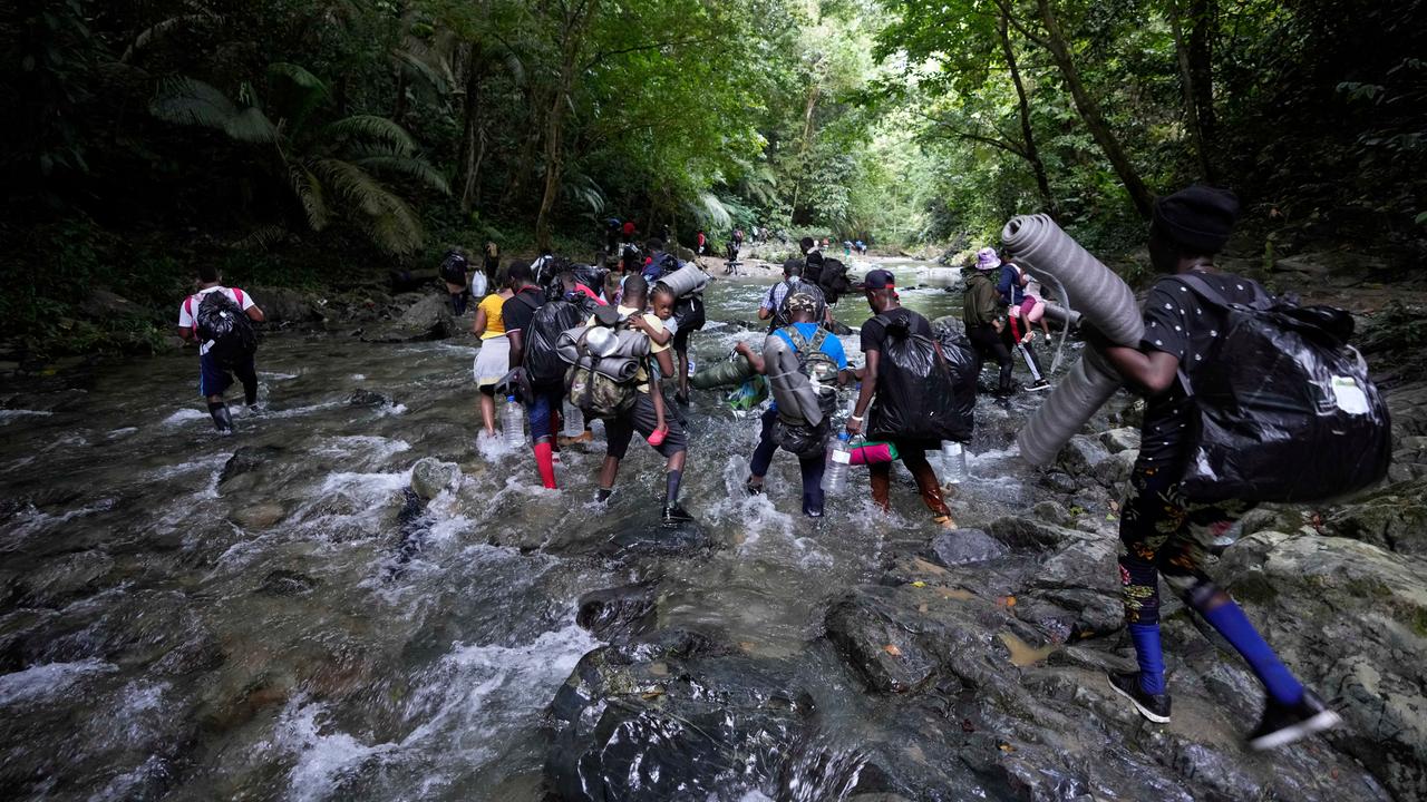 Migranten aus Haiti durchqueren auf dem Weg durch den Darién Gap im Dschungel zwischen Kolumbien und Panama einen Fluss.