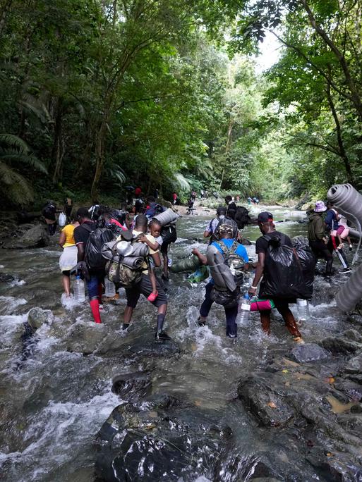 Migranten aus Haiti durchqueren auf dem Weg durch den Darién Gap im Dschungel zwischen Kolumbien und Panama einen Fluss.