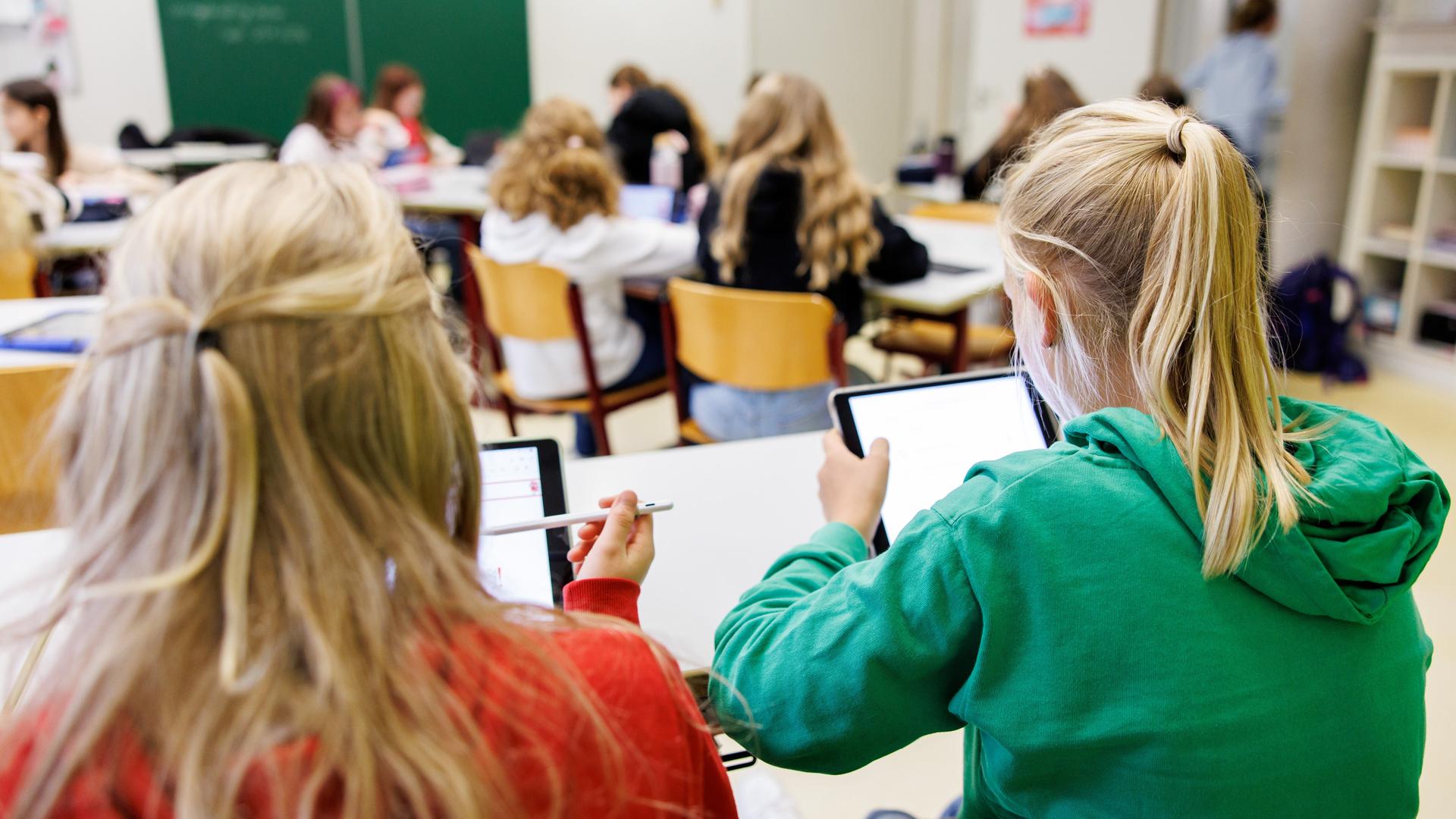 Schülerinnen einer sechsten Klasse arbeiten in einem Klassenraum an ihren Tablets. Schülerinnen einer sechsten Klasse arbeiten in einem Klassenraum an ihren Tablets.