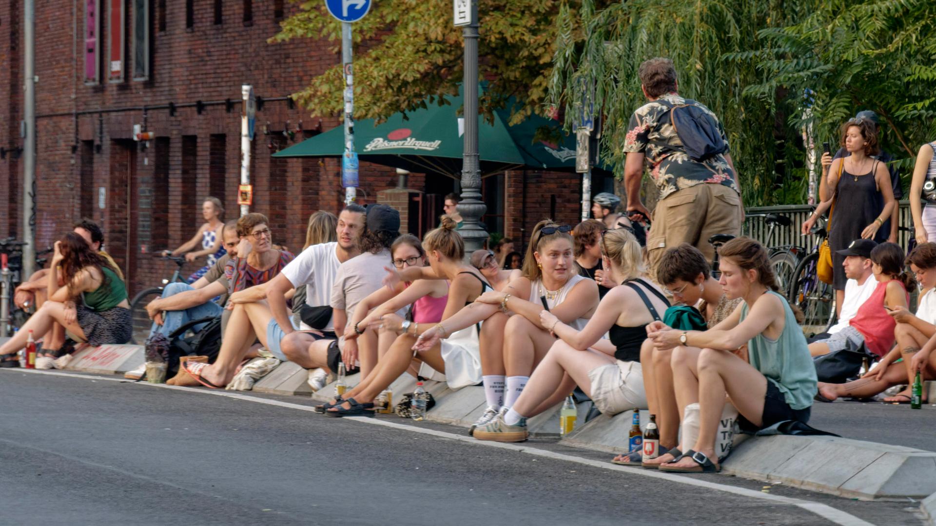 Viele junge Menschen sitzen auf dem Straßenpflaster der Berliner Hobrechtbrücke, Hot Spot, Sommer in Berlin, zwischen Berlin-Neukölln und Berlin-Kreuzberg. Viele junge Menschen sitzen auf dem Straßenpflaster der Berliner Hobrechtbrücke, Hot Spot, Sommer in Berlin, zwischen Berlin-Neukölln und Berlin-Kreuzberg.