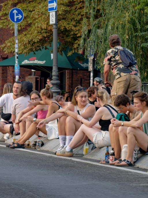 Viele junge Menschen sitzen auf dem Straßenpflaster der Berliner Hobrechtbrücke, Hot Spot, Sommer in Berlin, zwischen Berlin-Neukoelln und Berlin-Kreuzberg. Viele junge Menschen sitzen auf dem Straßenpflaster der Berliner Hobrechtbrücke, Hot Spot, Sommer in Berlin, zwischen Berlin-Neukoelln und Berlin-Kreuzberg.