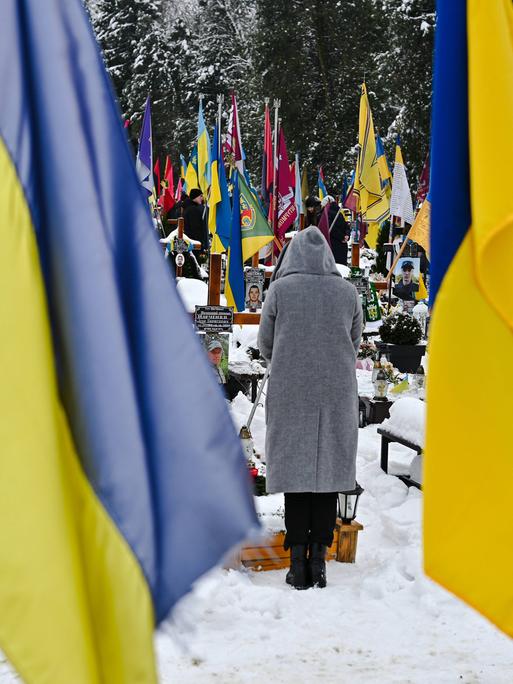 Besucher eines Friedhofs in Lwiw gedenken der Toten des aktuellen Krieges in der Ukraine. Der Friedhof ist geschmückt mit ukrainischen Nationalflaggen. 