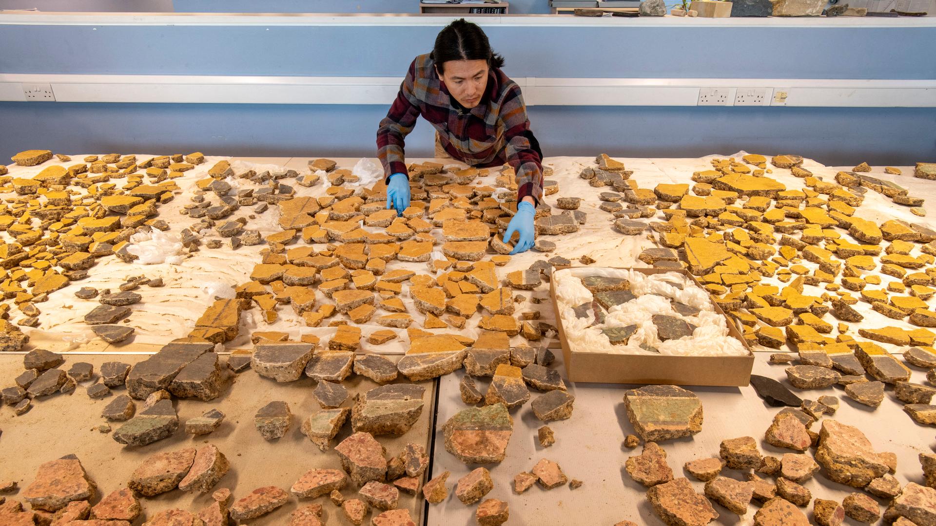 Das Foto zeigt einen Archäologen, der die Fragmente des Wandgemäldes sortiert. Photo by Handout / Museum of London Archaeology (MOLA) / AFP) / RESTRICTED TO EDITORIAL USE - MANDATORY CREDIT "AFP PHOTO / 