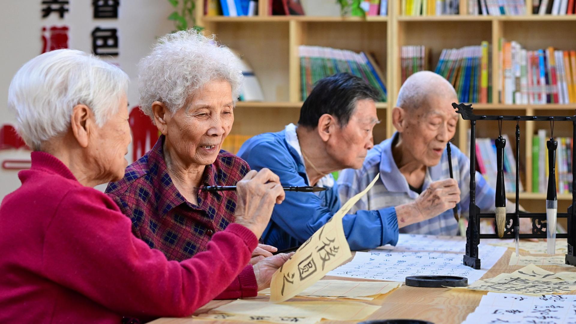 China: Vier Senioren sitzen nebeneinander und beschäftigen sich mit Kalligraphien. China: Vier Senioren sitzen nebeneinander und beschäftigen sich mit Kalligraphien.