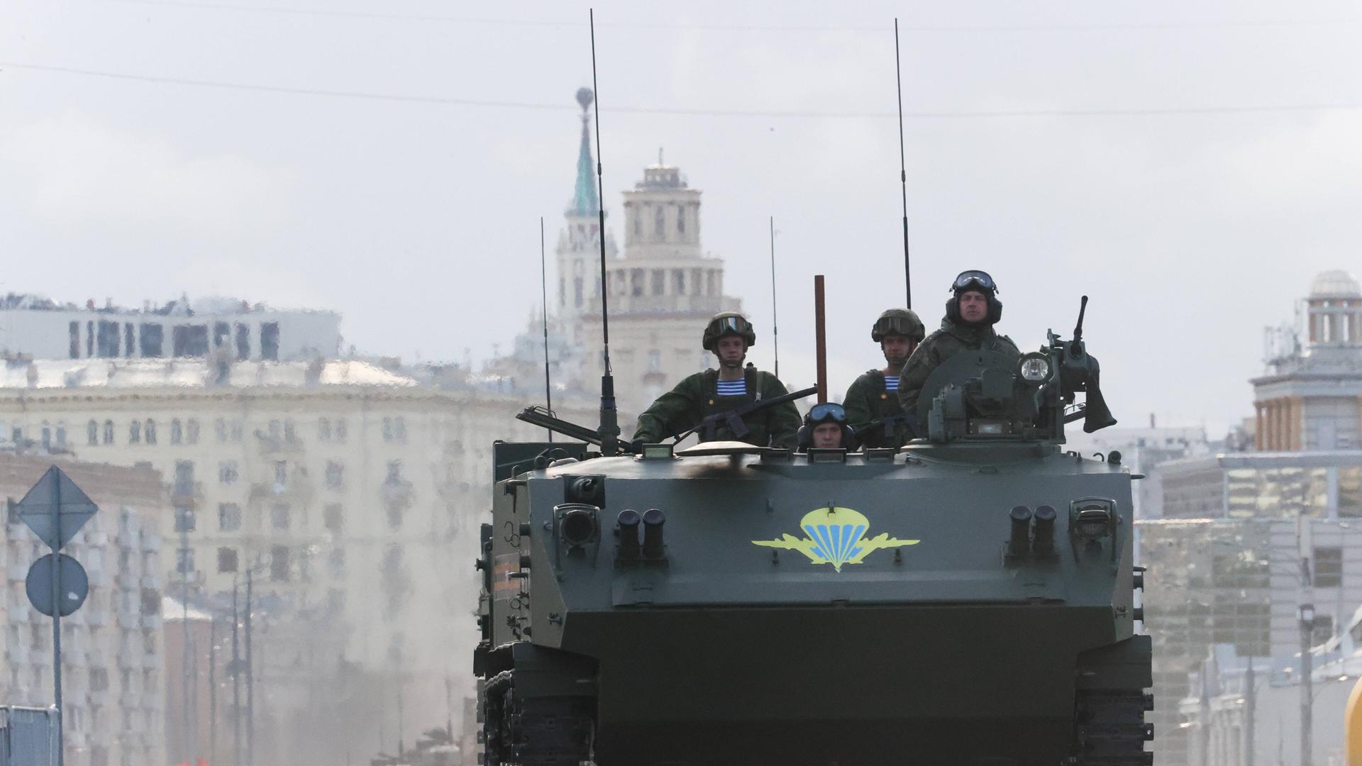 Vier russische Soldaten fahren mit einem Militärfahrzeug auf den Roten Platz in Moskau, um an der Siegesparade zum 9. Mai teilzunehmen. 
