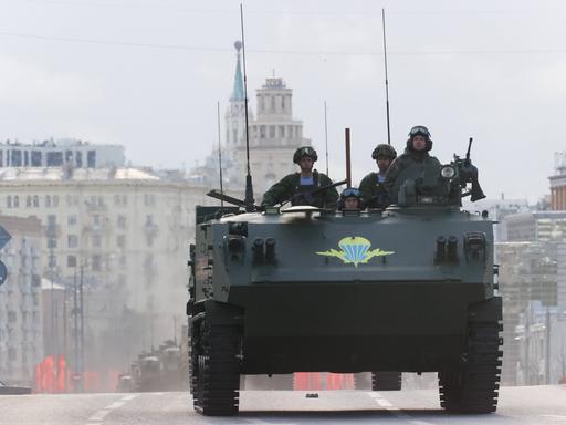 Vier russische Soldaten fahren mit einem Militärfahrzeug auf den Roten Platz in Moskau, um an der Siegesparade zum 9. Mai teilzunehmen. 
