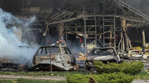 Ein Mann versucht nach einem russischen Angriff auf die ukrainische Stadt Saporischschja ein Feuer zu löschen.