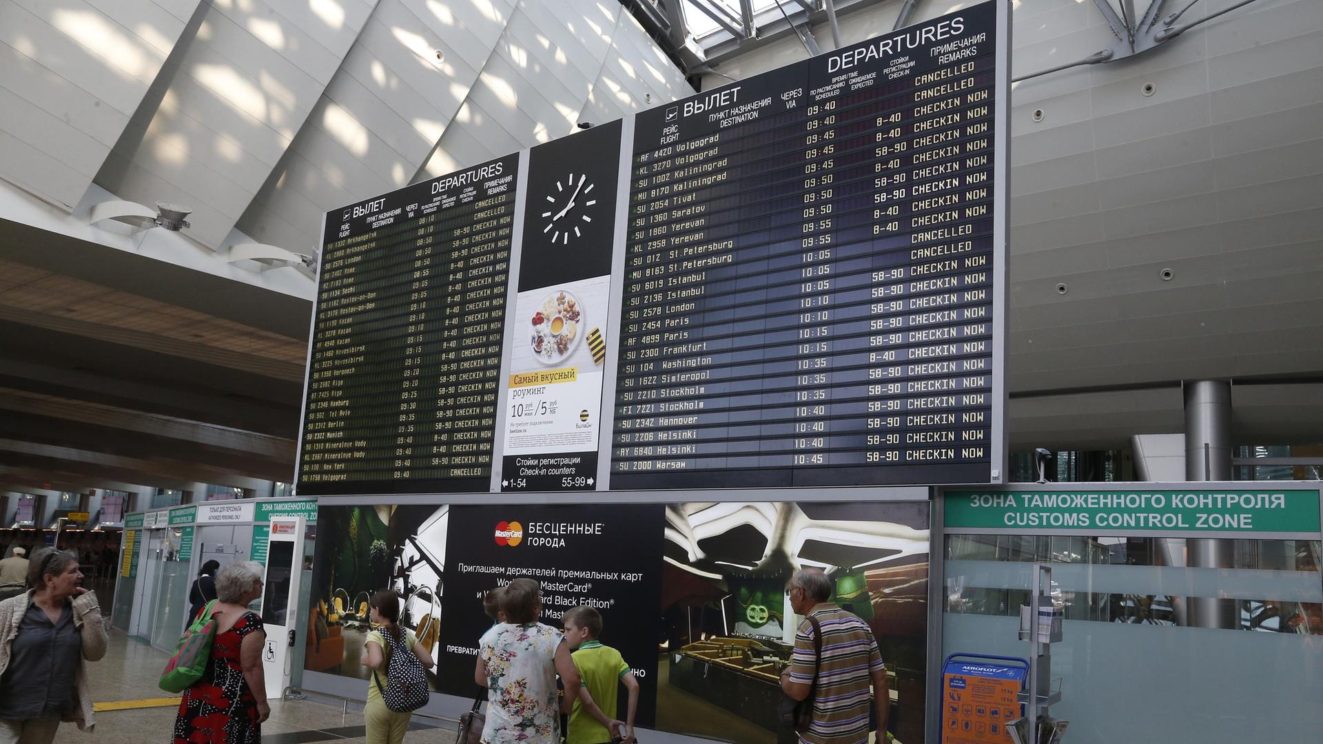 Menschen stehen an einer Informationstafel am Flughafen Scheremetjewo in Moskau, Russland. Menschen stehen an einer Informationstafel am Flughafen Scheremetjewo in Moskau, Russland.