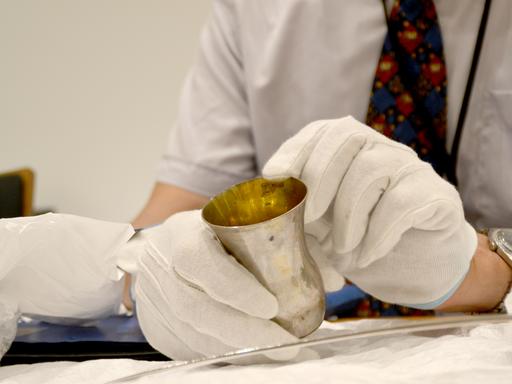 Matthias Weniger, Leiter der Provenienzforschung des Bayerischen Nationalmuseums, zeigt einen in der NS-Zeit geraubten Silberbecher, den er mit weißen Handschuhen hält. 