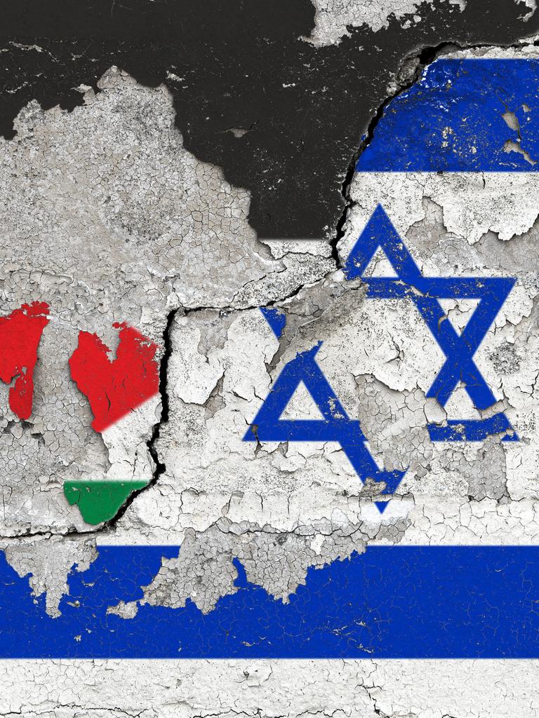 Die Nationalflaggen von Palaestina und Israel auf einer Wand mit aufgeplatzter Farbe und einem schraegen, dicken Riss.