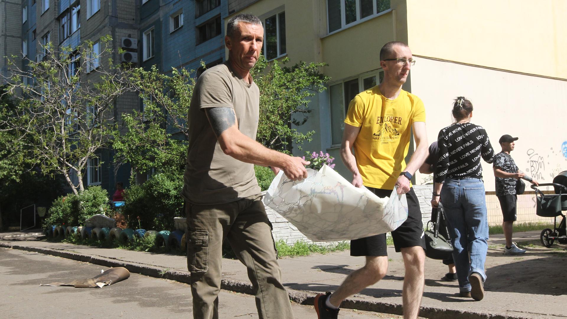 Nach einem russischen Drohnenangriff in Kamianske in der Region Dnipropetrowsk tragen zwei Männer Schutt beiseite. Das Foto entstand am 26. April 2025.