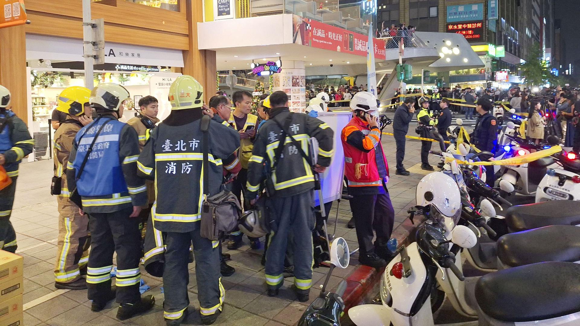 Rettungskräfte und Polizisten stehen auf einer Straße.