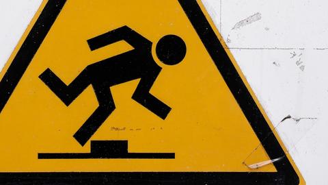 Ein Warnschild, gelbes Dreieck darin ein stolpender Mann: Achtung, Stolpergefahr!