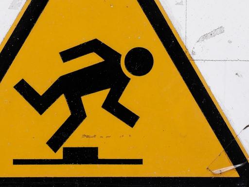 Ein Warnschild, gelbes Dreieck darin ein stolpender Mann: Achtung, Stolpergefahr!