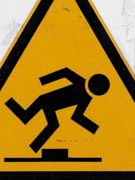 Ein Warnschild, gelbes Dreieck darin ein stolpender Mann: Achtung, Stolpergefahr!