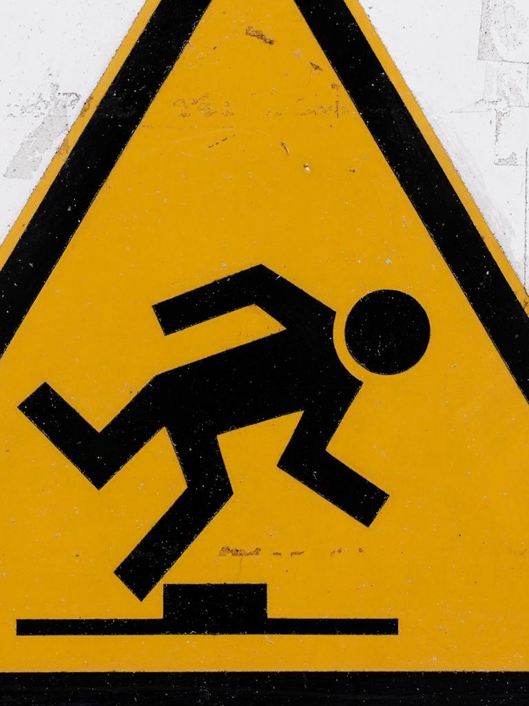 Ein Warnschild, gelbes Dreieck darin ein stolpender Mann: Achtung, Stolpergefahr!
