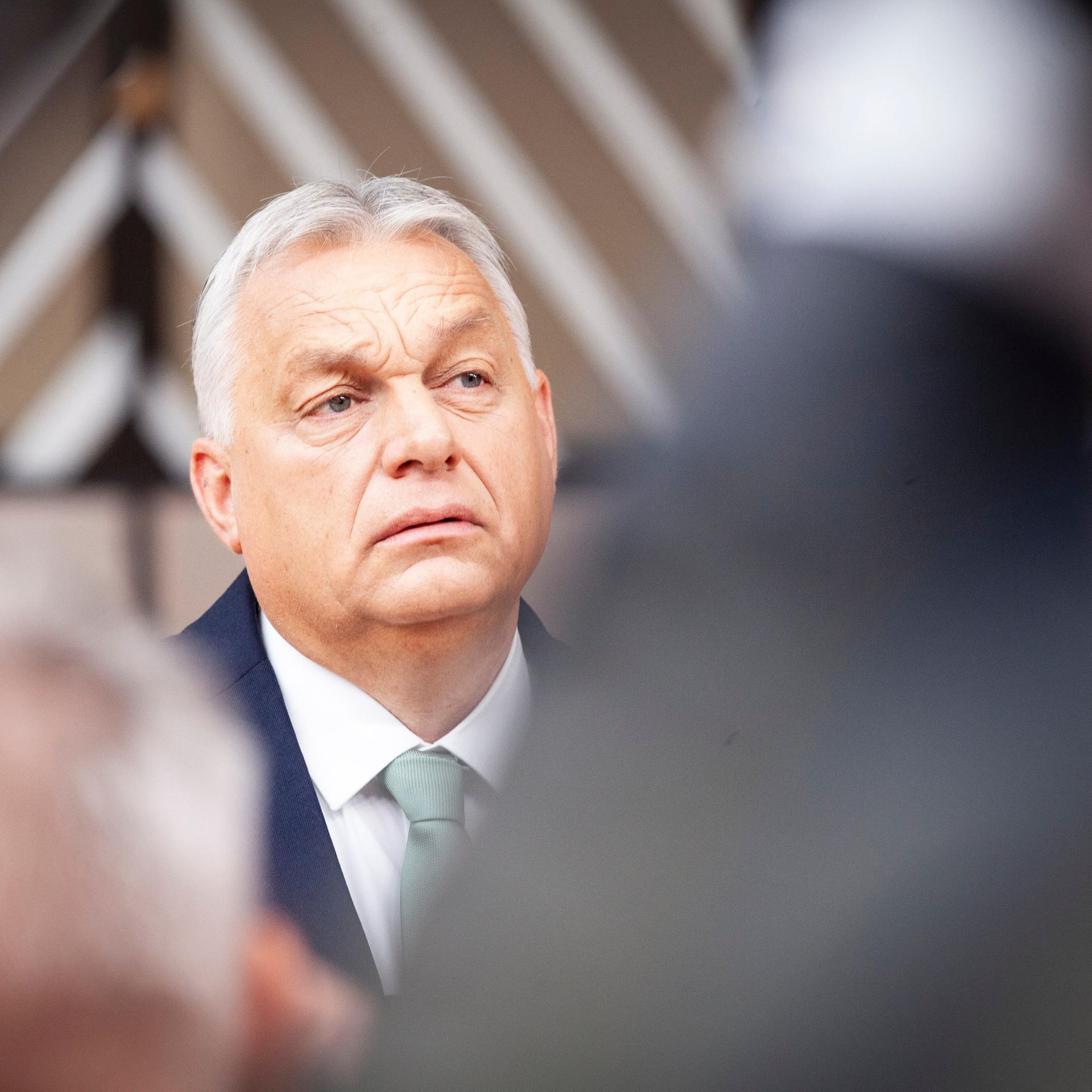 Portrait von Viktor Orban. Er trägt eine dunkle Anzugsjacke und ein weißes Hemd