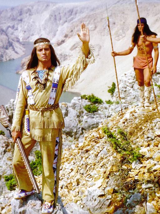 Der Schauspieler Pierre Brice steht als Häuptling Winnetou in einem Film aus dem Jahre 1963 vor einer Schlucht mit erhobener Hand.
