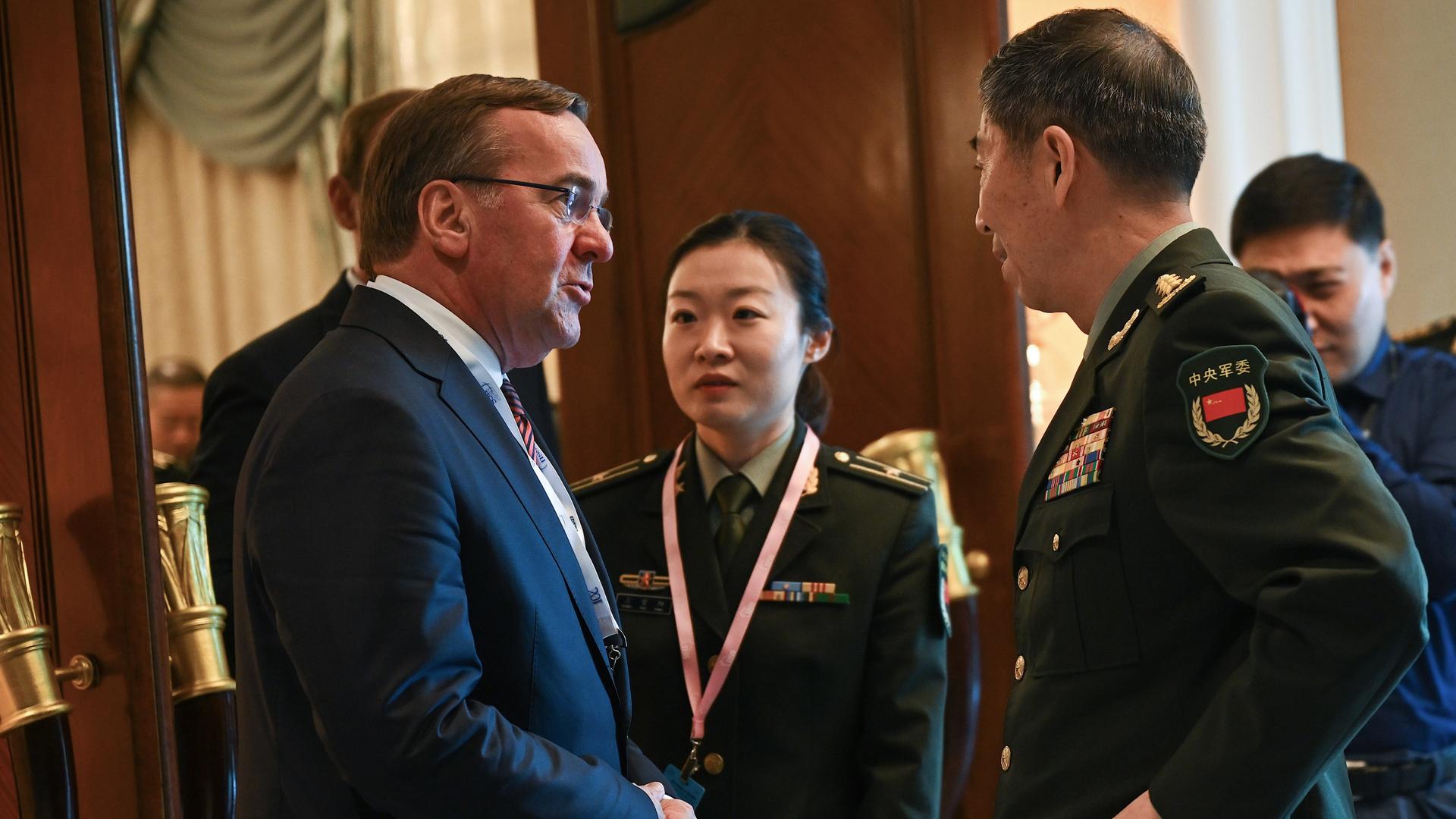 Das Foto zeigt Verteidigungsminister Boris Pistorius und den chinesischen Verteidigungsminister Li Shangfu. Sie stehen sich gegenüber und sprechen miteinander. Im Hintergrund ist eine chinesische Soldatin zu sehen.