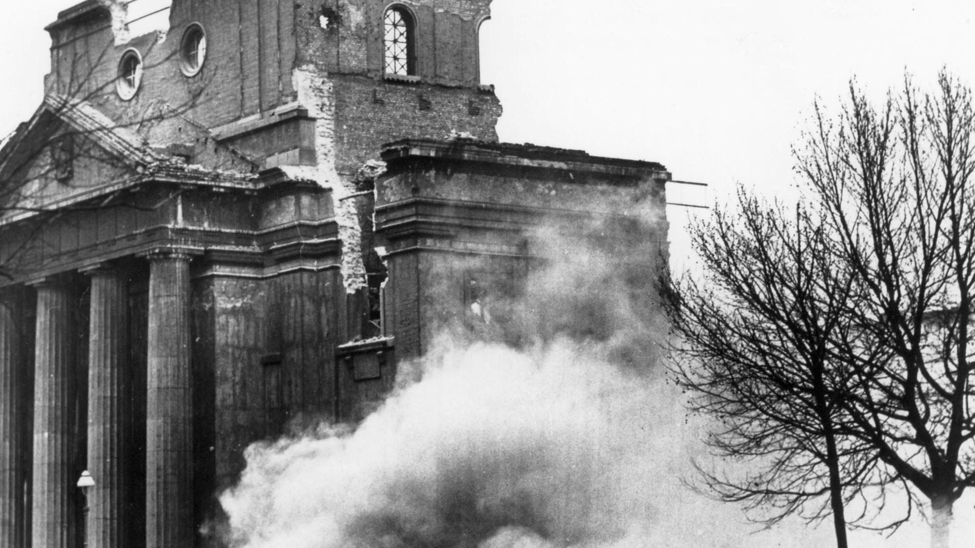 Historisches Schwarzweißfoto einer ruinösen Synagoge, die gesprengt wird.