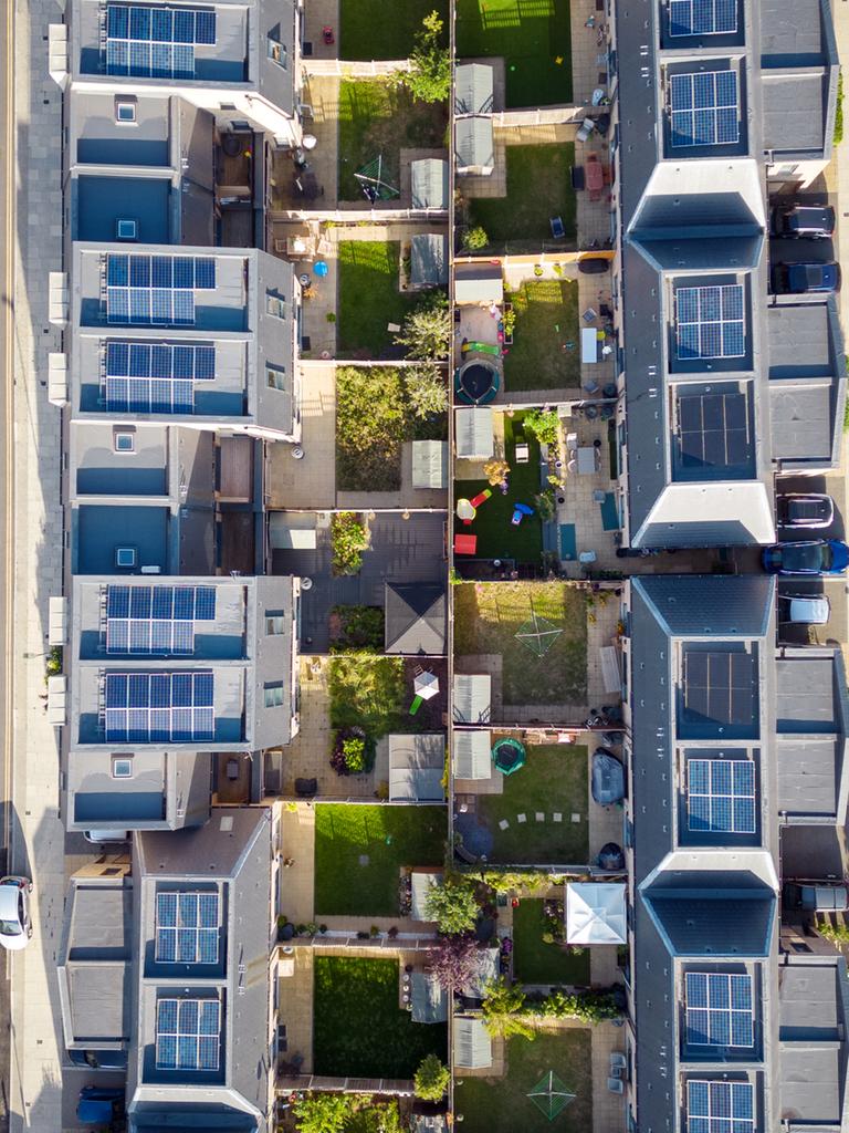 Luftaufnahme einer Reihenhaussiedlung, in der jedes Haus Solarzellen auf dem Dach hat.