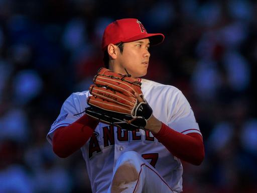 Das Foto zeigt Baseballspieler Shohei Ohtani  im Trikot der Los Angeles Angels im Profil, während er sich für einen Wurf bereit macht.
