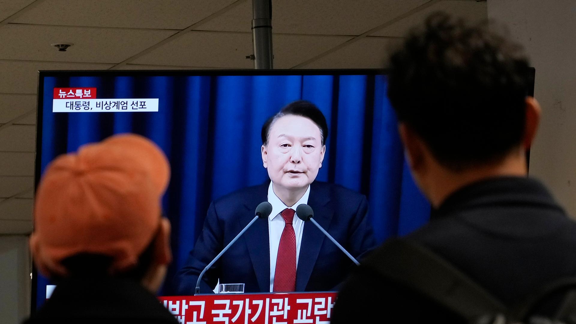 Menschen schauen auf einen Fernsehbildschirm, der die Ansprache des südkoreanischen Präsidenten Yoon Suk Yeol zeigt