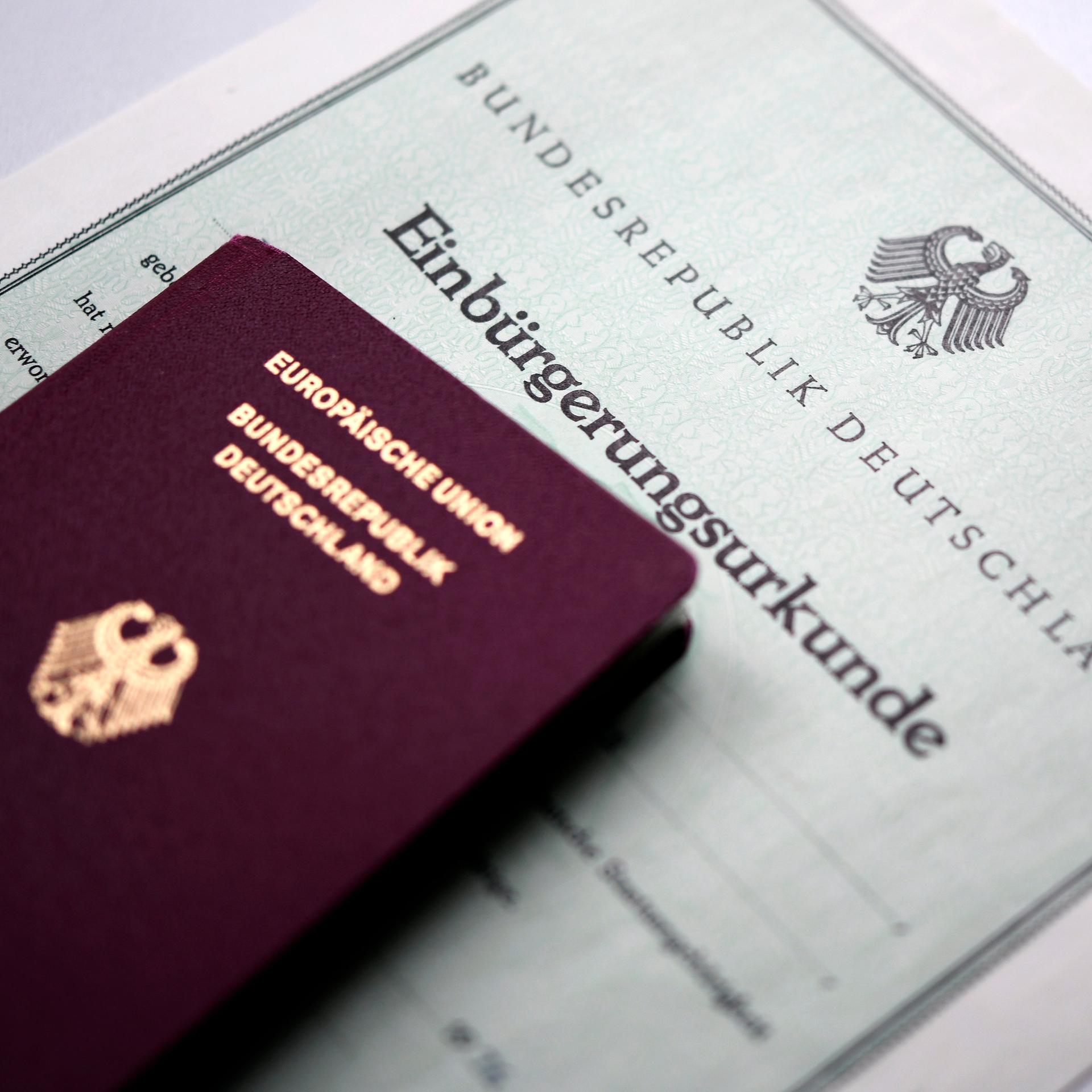 Ein Reisepass liegt auf einer Einbürgerungsurkunde.