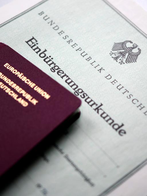 Ein Reisepass liegt auf einer Einbürgerungsurkunde.
