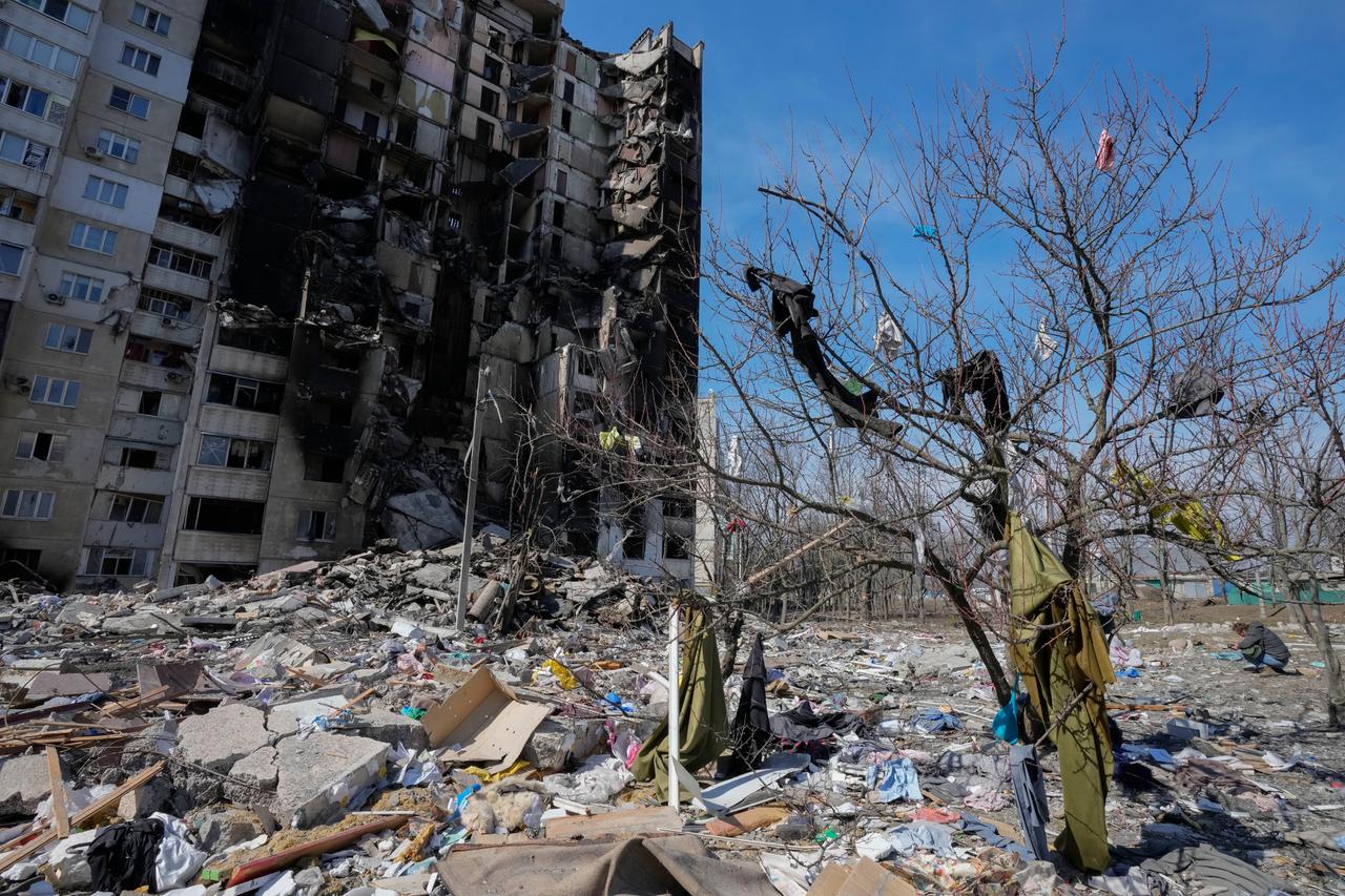 Kleidung, die durch russischen Beschuss aus einem ausgebrannten Haus in Charkiw in der Ostukraine auf einen Baum geschleudert wurde, und dahinter das bombardierte Haus.