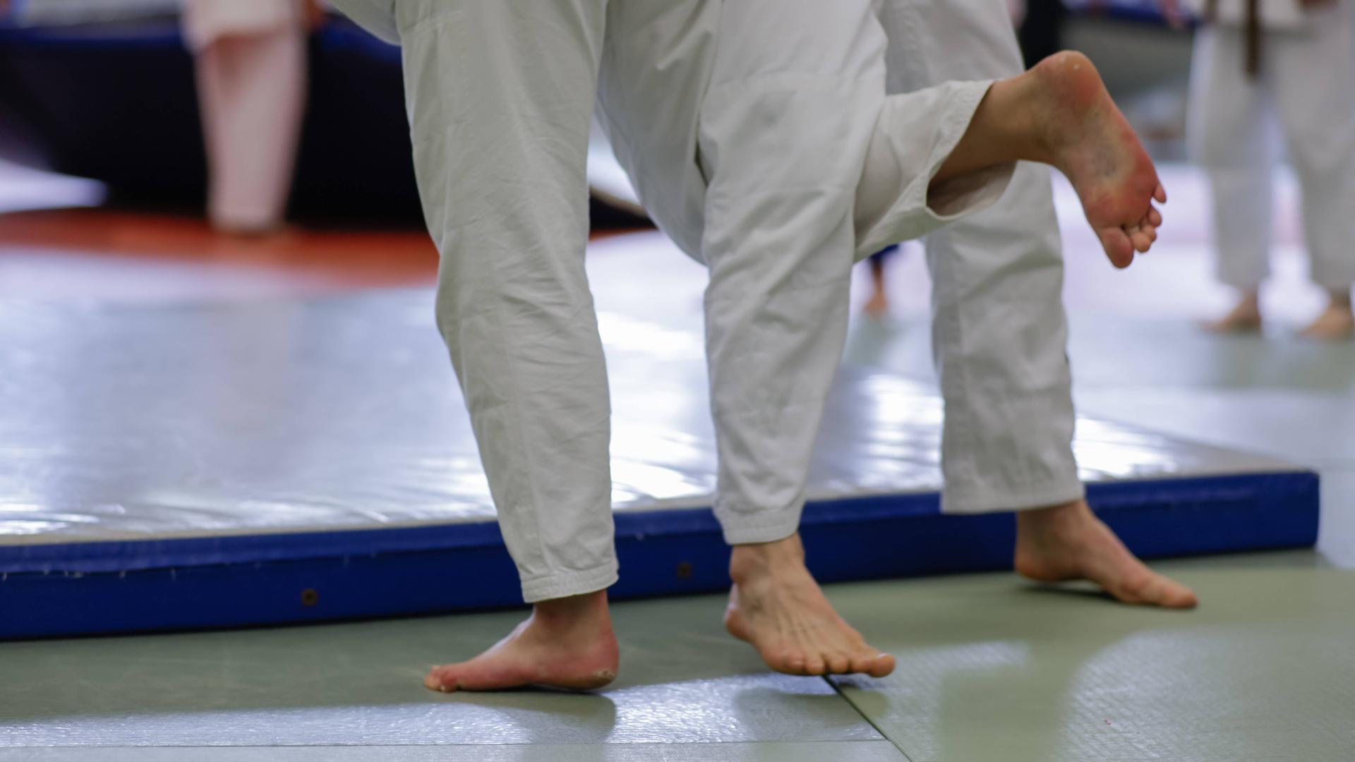 Nahaufnahme eines Judokampfes: Verhakte Füße scheinen einen Wurf vorzubereiten.