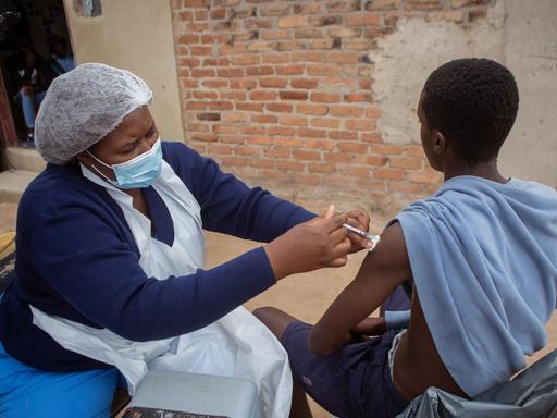 Eine mobile Impfstation in Harare, Simbabwe: Eine Krankenschwester impft einen jungen Mann gegen Corona. 