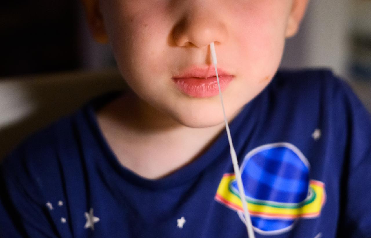 Ein fünfjähriger Junge führt für einen Corona-Selbsttest ein Stäbchen zum Abstrich in seine Nase (gestellte Szene).
