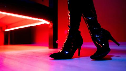 Eine Prostituierte steht vor der roten Beleuchtung unter einem Bett in einem Studio.