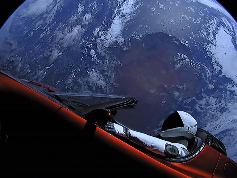 Roter Tesla Roadster im Weltraum mit der Erde im Hintergrund und einem Raumfahrer auf dem Fahrersitz