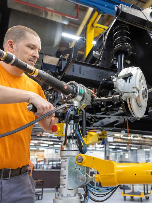 Ein Mitarbeiter montiert Antriebsstränge in der Produktionsstraße von Elektronutzfahrzeugen im Werk der Neapco Europe GmbH (Automobilzulieferer) in Düren.