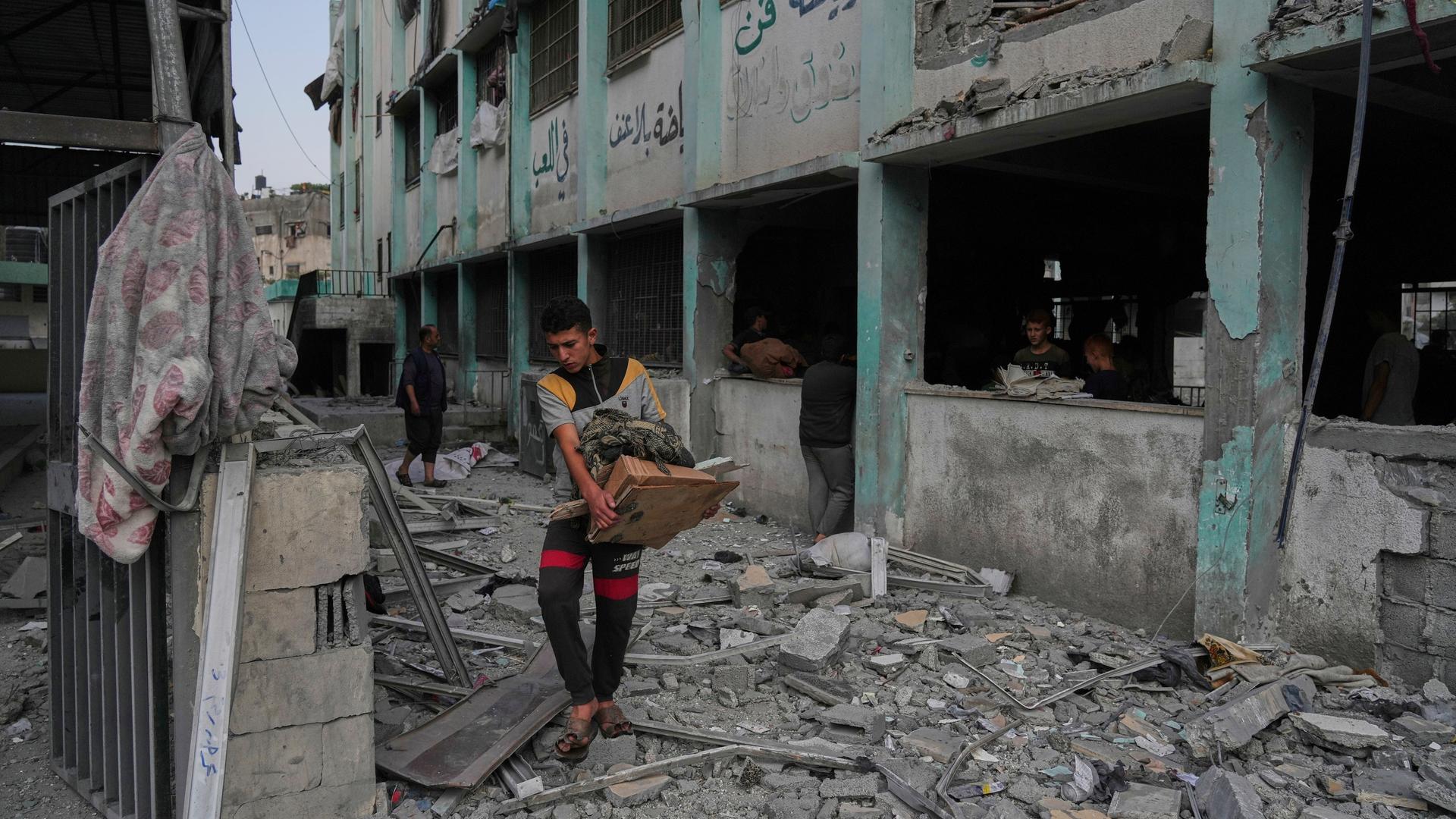 Ein palästinensischer Jugendlicher in einer zerstörten Schule im Gazastreifen, die vom israelischen Militär demoliert worden war. Rundherum sind nur Trümmer. 