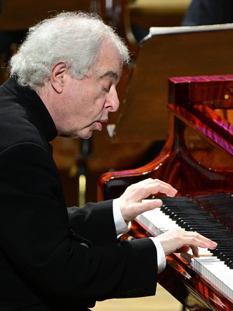 Der Pianist András Schiff sitzt an einem schwarzen Flügel und spielt. Er sitzt leicht nach vorne gebeugt und schaut sehr konzentriert. 
