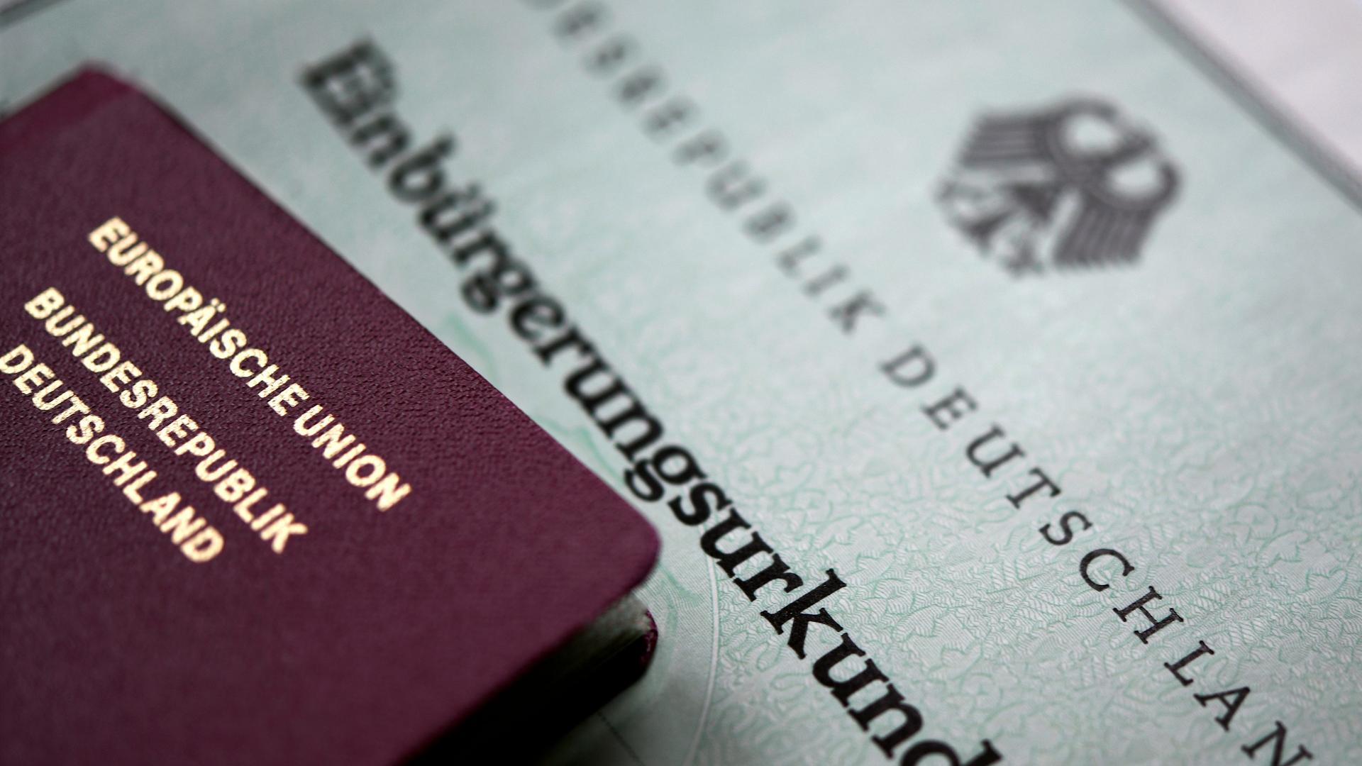 Ein deutscher Reisepass und eine Einbürgerungsurkunde liegen übereinander.