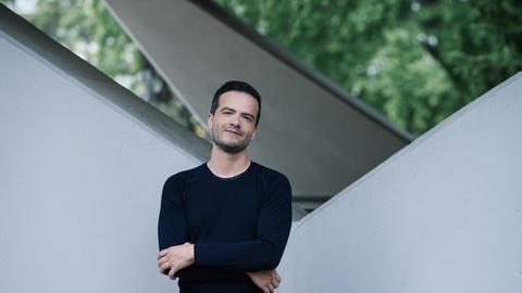 Francesco Piemontesi steht vor einem Gebäude und lächelt in die Kamera,