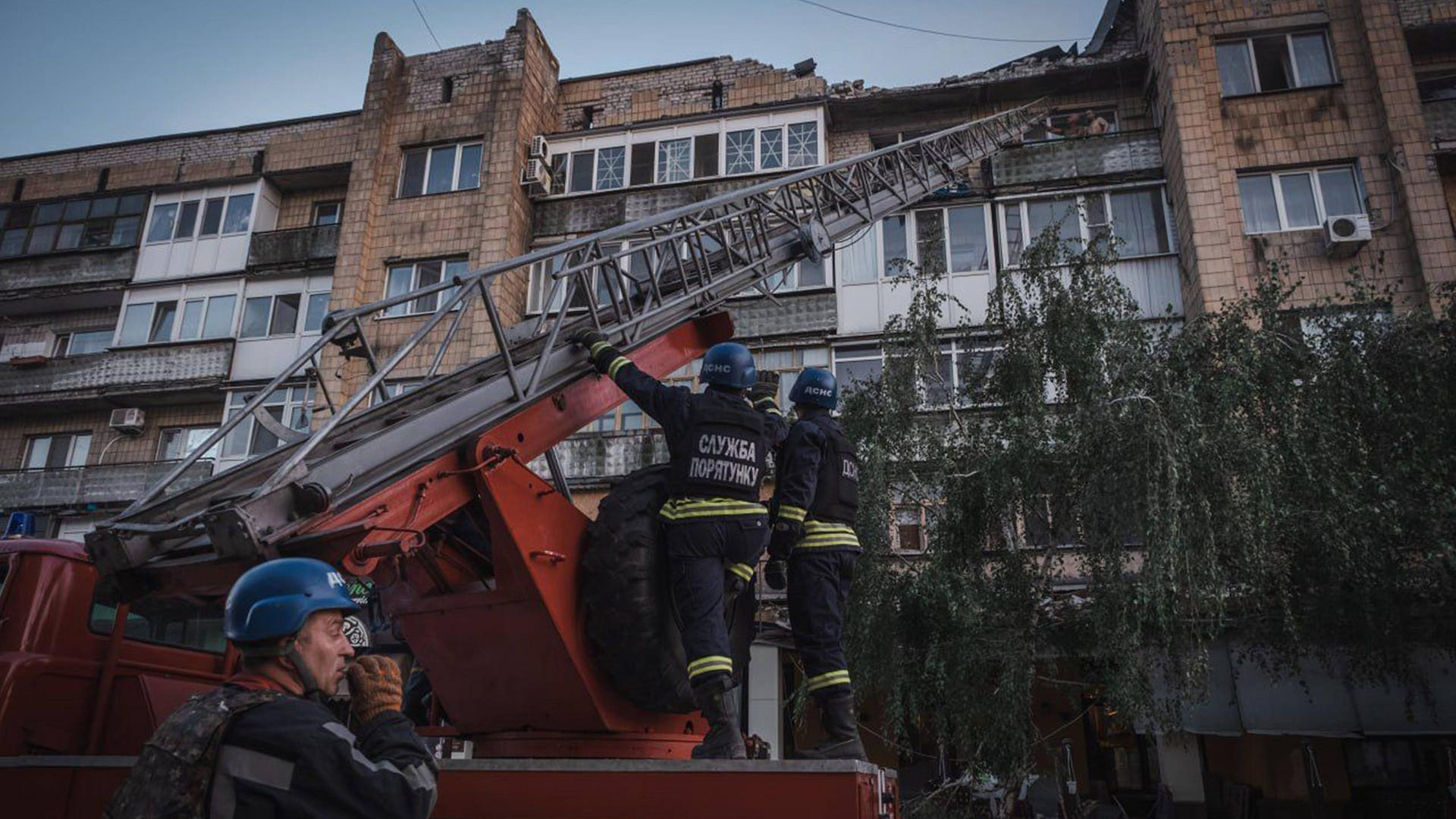 Ukrainische Nothelfer der Feuerwehr im Einsatz vor einem beschädigten Haus. 