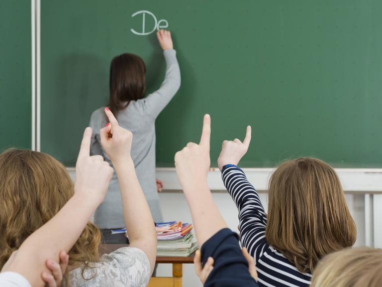 Klassenzimmer mit Tafel, Schüler melden sich. Klassenzimmer mit Tafel, Schüler melden sich.
