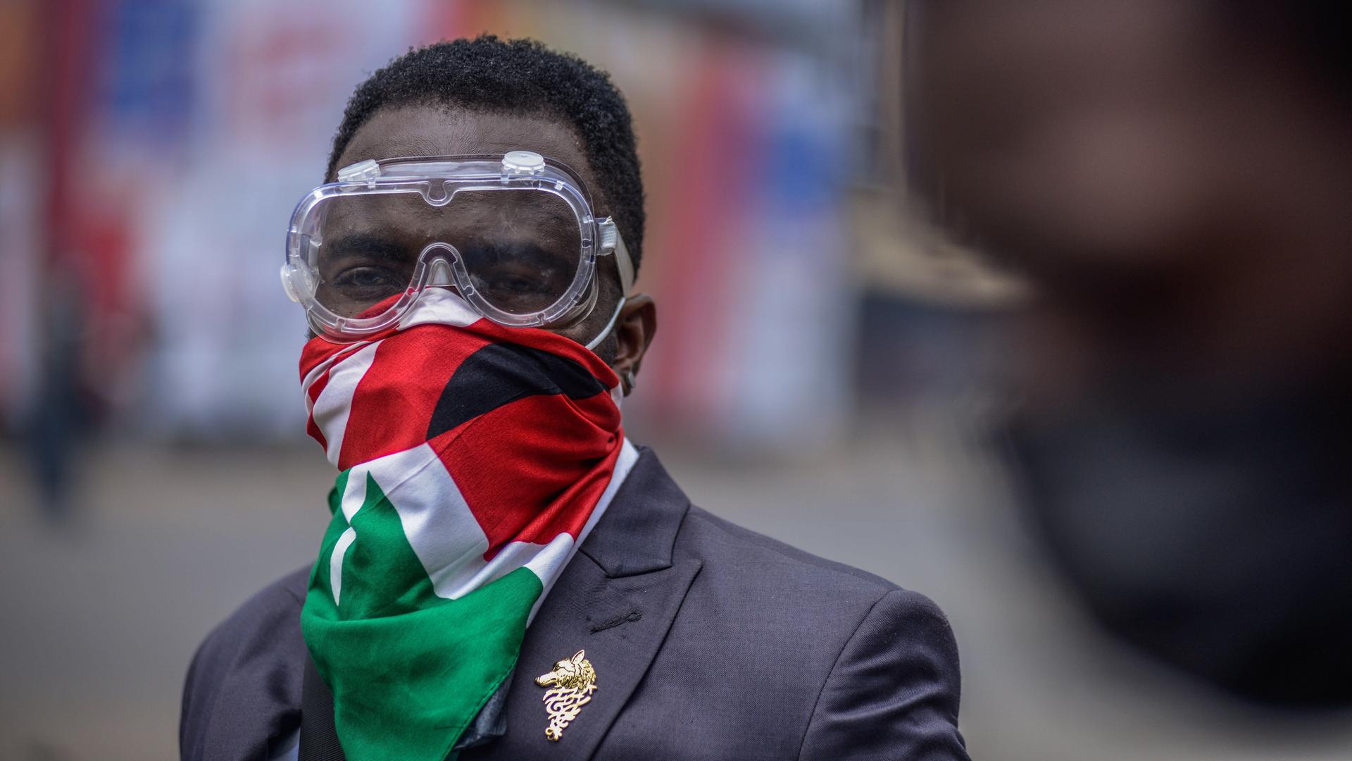 Ein Demonstrant trägt eine Schutzbrille und eine kenianische Flagge vor Mund und Nase.