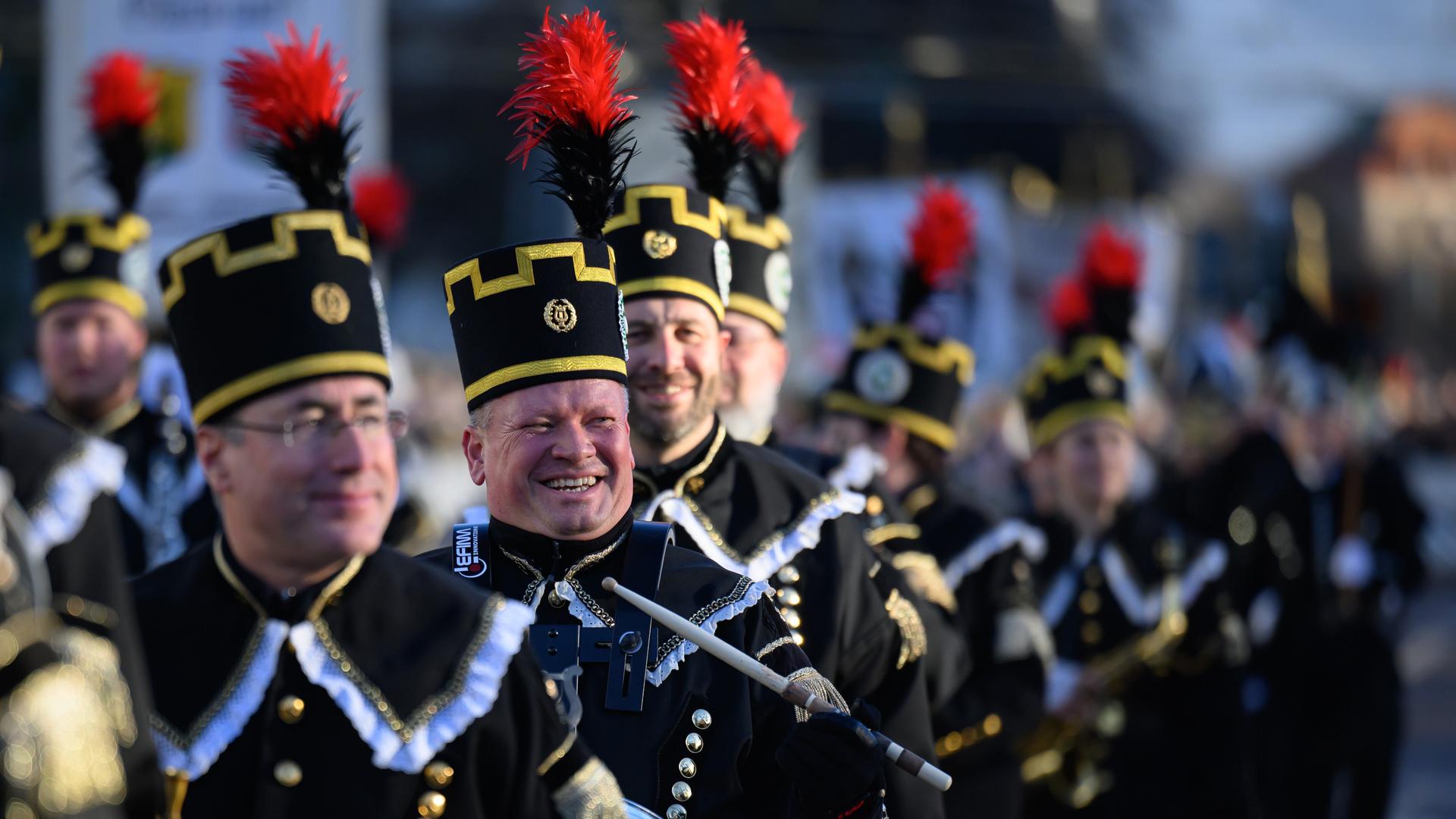 Teilnehmer der Bergparade gehen nebeneinander. Sie sind in traditioneller Bergmanns-Uniform gekleidet. Teilnehmer der Bergparade gehen nebeneinander. Sie sind in traditioneller Bergmanns-Uniform gekleidet.