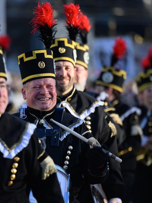 Teilnehmer der Bergparade gehen nebeneinander. Sie sind in traditioneller Bergmanns-Uniform gekleidet.