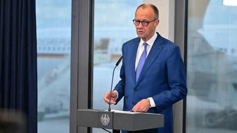 Bundeskanzler Friedrich Merz gibt vor seinem Abflug zum G7-Gipfel am militärischen Teil des Flughafens Berlin Brandenburg ein Statement. Er steht an einem Pult und spricht in ein Mikrofon.